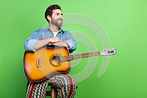 Photo of cheerful handsome guy wear denim jacket enjoy guitar music looking empty space isolated green color background