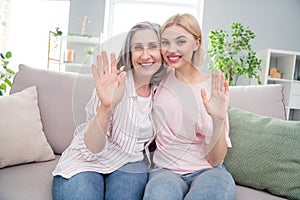 Photo of cheerful happy nice old lady and young woman wave hello good mood harmony indoors inside house home