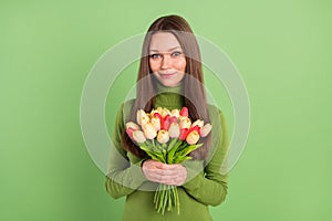 Photo of cheerful happy young nice lady hold hands bunch tulips spring  on green color background