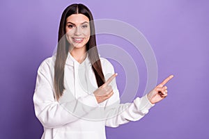 Photo of cheerful happy young woman point finger index empty space smile isolated on purple color background
