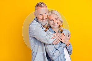 Photo of cheerful joyful happy old couple hug embrace care enjoy harmony hands isolated on yellow color background