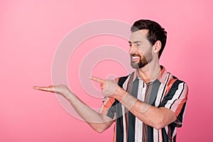 Photo of cheerful male business owner demonstrate empty blank space on hand finger pointing project isolated over pink