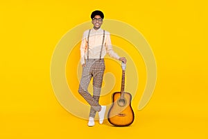 Photo of cheerful musician guy posing hold guitar wear suspenders shirt isolated yellow color background