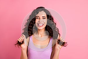 Photo of cheerful nice cute ecstatic girlfriend holding ends of her hair while isolated with pink background