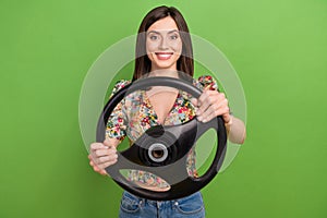 Photo of cheerful pretty girl toothy smile hands hold wheel isolated on green color background