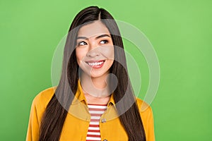 Photo of cheerful pretty young woman look empty space bite lip teeth creative isolated on green color background