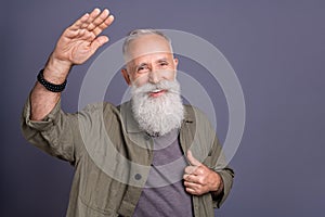 Photo of cheerful senior man good mood waving arm hello casual clothes isolated over grey color background
