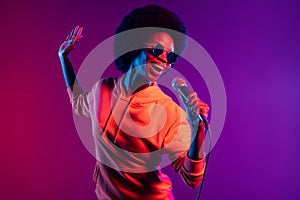 Photo of cheerful singer lady hold mic open mouth wear hoodie eyeglasses  gradient neon background