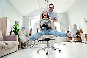 Photo of cheerful smiling colleagues formalwear riding office chair indoors workplace workshop