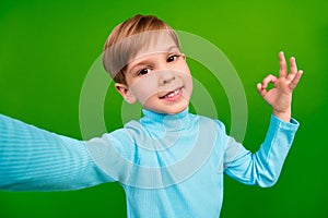 Photo of cheerful sweet little grandson dressed teal turtleneck recoding self video showing okey  green color