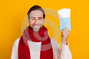 Photo of cheerful tourist guy hold tickets prepare travel wear red scarf white sweater isolated yellow color background