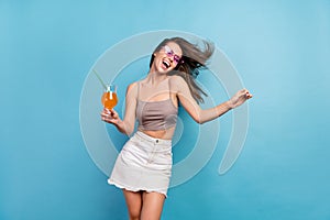 Photo of cheerful young crazy woman fly wind blow hair hold drink dance smile isolated on blue color background