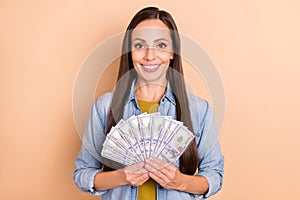 Photo of cheerful young lady hold money fan of dollars lottery winner jackpot isolated on beige color background