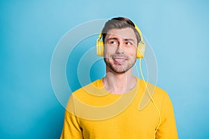 Photo of cheerful young man listen to music look empty space toothy smile isolated on blue color background