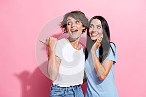 Photo of cheerful young shocked sisters indicating finger empty space look curious crazy low price promo isolated on
