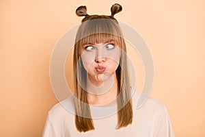 Photo of childish playful stupid girl inflate cheeks squint wear t-shirt isolated beige color background