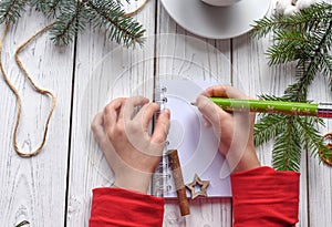 A photo of children`s hands writing in a note book, a cuo of tea anf Christmas decoration