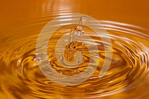 Photo of circles on the water from a fallen drop of water. Yellow, golden background.