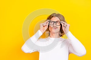 Photo of clever intelligent male in eyeglasses look empty space considering new idea isolated on yellow color background