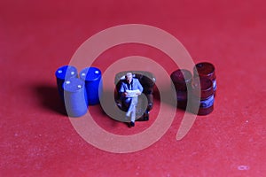 Photo Close Up, Scale HO Sitting old Businessman Beyond Red and Blue Oil Barrel, for your element design oil or fuel related