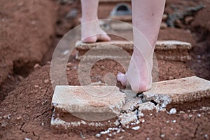 shards of a broken concrete block at woman barefoot at the walking