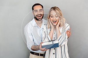 Photo closeup of happy man in casual clothing smiling and giving present to his girlfriend