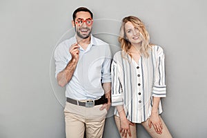 Photo closeup of laughing couple in casual clothing posing with paper fake glasses on stick