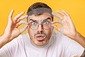 Photo closeup of shocked young man in eyeglasses looking at camera