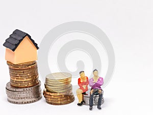 Photo of coins with miniature house and human isolated on white background.