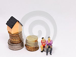 Photo of coins with miniature house and human  on white background.