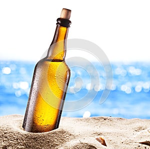 Photo of cold beer botle in the sand.