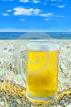 Photo of cold beer bottle in the sand on the beach