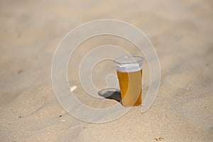 Photo of cold beer in the hot sand. Drops of water on glass. Thirsty concept. Summer time. Holiday. Copy space