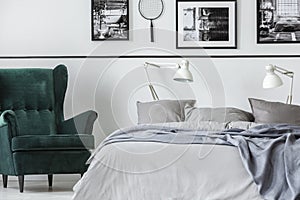 Photo collector bedroom with emerald armchair and king size bed with grey bedding