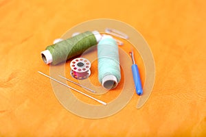 Photo of colored sewing thread, needle, bobbin, button, safety pin and needle ripper