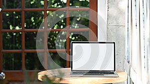 Photo of computer laptop with white blank screen putting outdoors on the modern table.