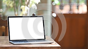 Photo of computer laptop with white blank screen putting outdoors on the modern table.