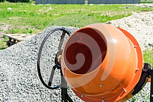 Photo concrete mixer installed on the construction site next to a pile of sand and gravel.