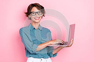 Photo of confidant lovely pretty girl with bob hairdo wear blue shirt eyeglasses comunicating on laptop isolated on pink