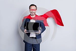 Photo of confident cheerful aged mature business guy super hero costume hold laptop presenting new device model sale