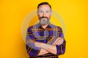 Photo of confident cheerful mature man hold hands crossed good mood smile isolated on yellow color background
