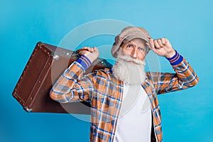 Photo of confident cool retired man dressed plaid suit holding suitcase arm headwear isolated blue color background