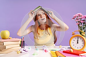 Photo of confused student girl holding exercise book on her head