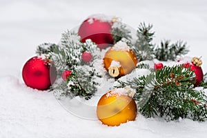Photo of the coniferous branches decorated with few big toys for the Christmas tree lying in the snow