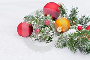 Photo of the coniferous branches decorated with three big toys for the Christmas tree lying in the snow