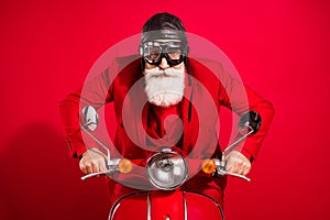 Photo of cool careful driver santa claus ride bike serious face wear goggles leather helmet suit on red color background