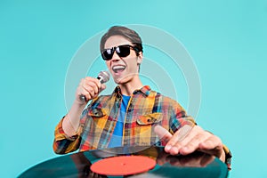 Photo of cool confident dj retro guy sing mic hand vinyl disk wear plaid shirt isolated aquamarine color background