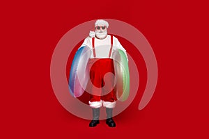 Photo of cool funky retired man wear santa claus costume smiling holding two inflatable cirkles isolated red color