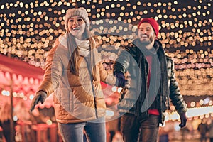 Photo of couple go walk christmas x-mas advent street event under evening outdoors lights wear season clothes