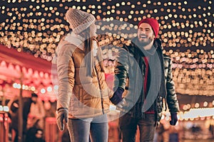 Photo of couple go walk under x-mas christmas evening outside advent illumination wear season coats